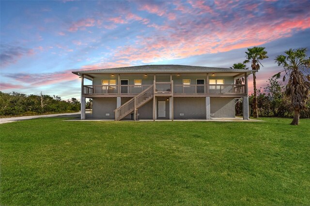 445 Horseshoe Loop Rd, Terra Ceia, FL 34250 - back of house at dusk with a lawn, stairway, and a wooden deck