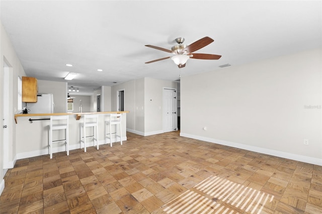 kitchen featuring kitchen peninsula, a kitchen breakfast bar, ceiling fan, light parquet flooring, and white fridge