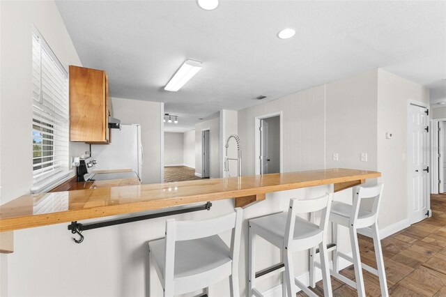 445 Horseshoe Loop Rd, Terra Ceia, FL 34250 - kitchen with range with electric cooktop, freestanding refrigerator, baseboards, a peninsula, and brown cabinets