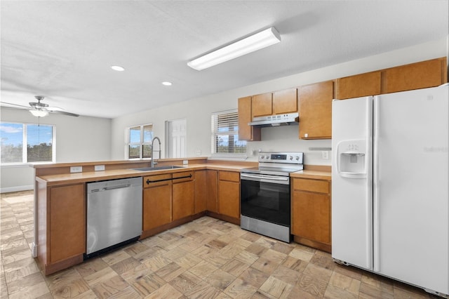 kitchen with kitchen peninsula, a textured ceiling, stainless steel appliances, ceiling fan, and sink