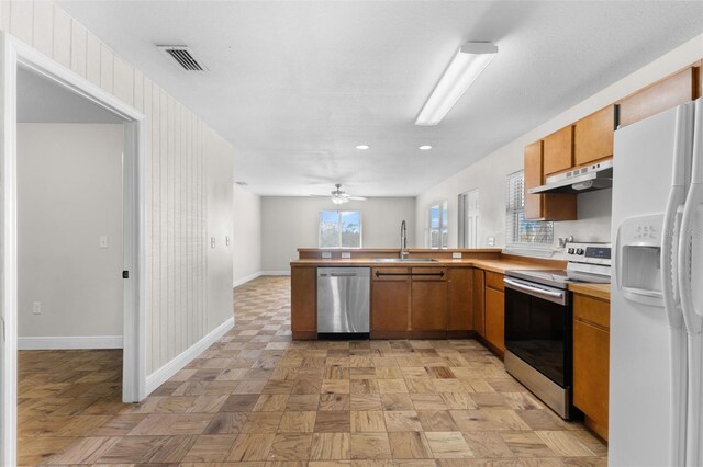 445 Horseshoe Loop Rd, Terra Ceia, FL 34250 - kitchen with appliances with stainless steel finishes, under cabinet range hood, a sink, baseboards, and a peninsula