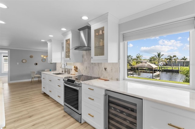 kitchen with wall chimney exhaust hood, sink, electric stove, a water view, and wine cooler