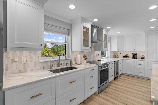 kitchen with electric range, sink, a healthy amount of sunlight, and wall chimney range hood