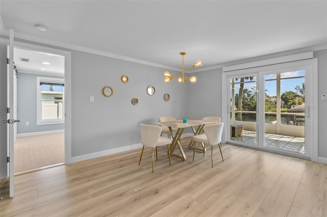 dining space with a barn door, a wealth of natural light, crown molding, and light hardwood / wood-style floors