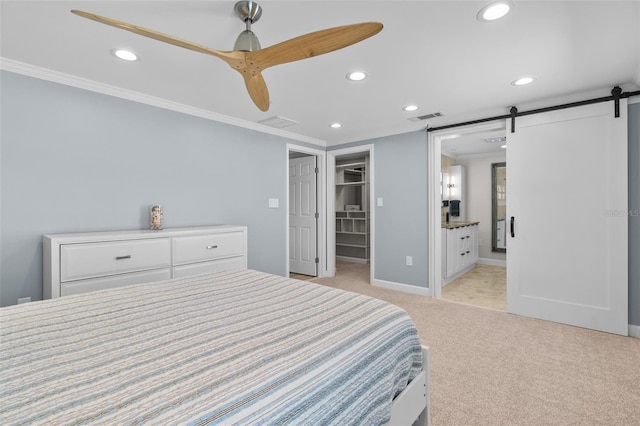 carpeted bedroom featuring ensuite bathroom, ceiling fan, a barn door, a spacious closet, and a closet