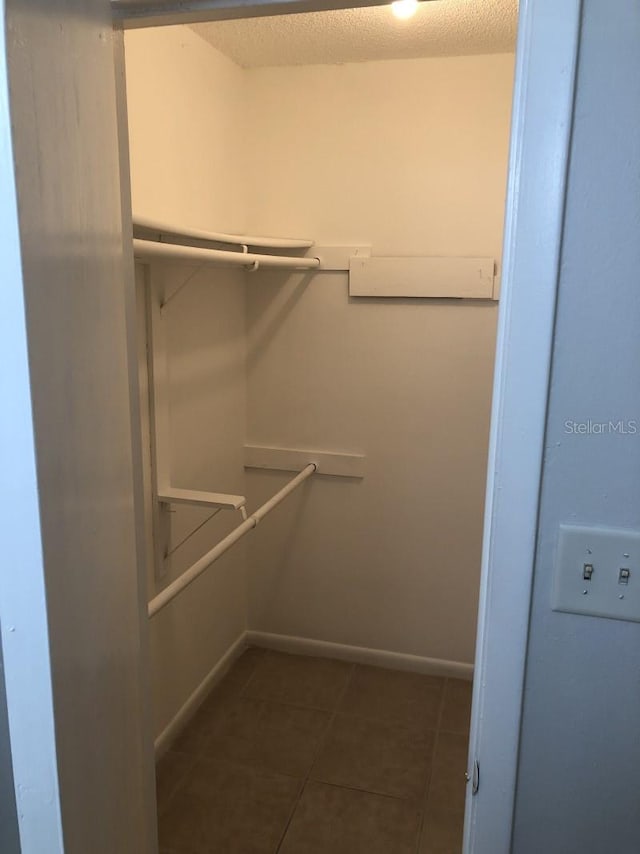 walk in closet with dark tile patterned flooring