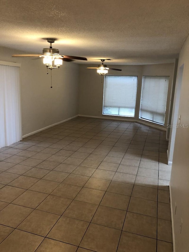 tiled empty room with ceiling fan and a textured ceiling