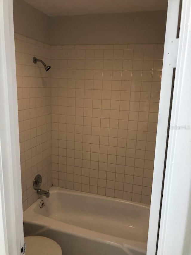 bathroom with toilet and tiled shower / bath