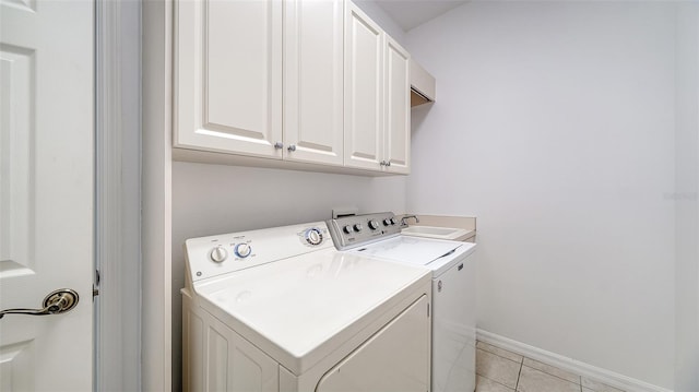 laundry room with cabinets, light tile patterned floors, and washing machine and clothes dryer