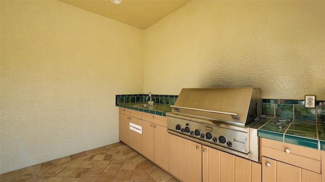 kitchen featuring light brown cabinetry, tile counters, and sink