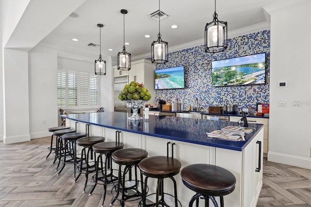 bar featuring pendant lighting, light parquet floors, white cabinets, crown molding, and sink