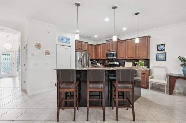 kitchen featuring light stone countertops, stainless steel appliances, an island with sink, decorative backsplash, and ornamental molding