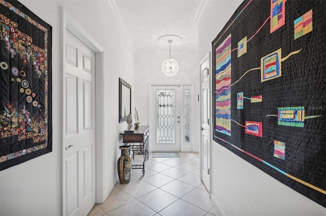 hallway with light tile patterned floors, an inviting chandelier, and ornamental molding