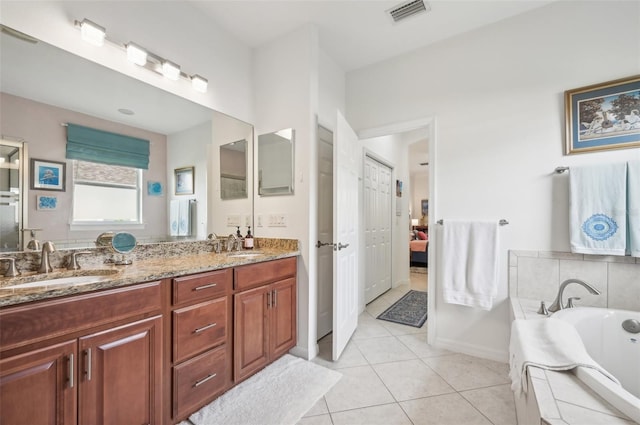 bathroom with tile patterned floors, tiled tub, and vanity