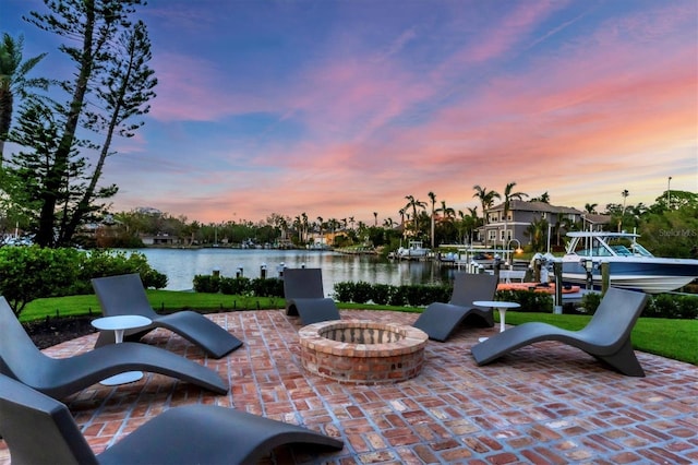 patio terrace at dusk with a water view and an outdoor fire pit