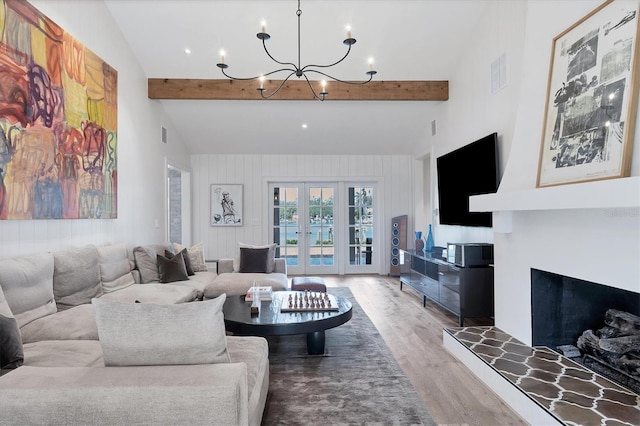 living room featuring french doors, a fireplace, hardwood / wood-style floors, vaulted ceiling with beams, and a chandelier