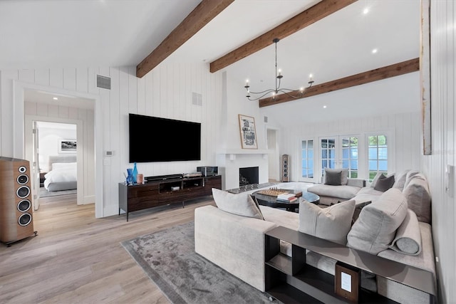 living room featuring vaulted ceiling with beams, wooden walls, light hardwood / wood-style flooring, and a notable chandelier