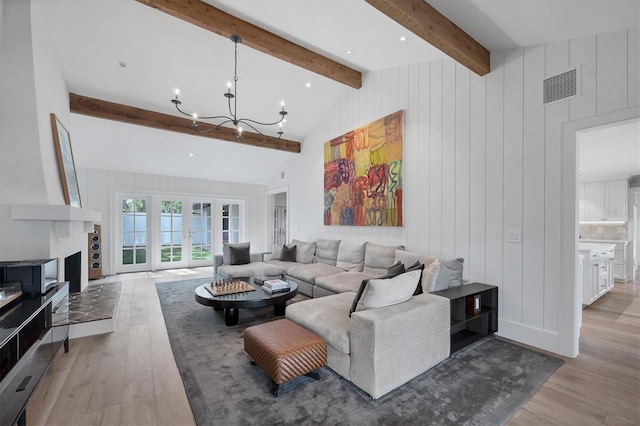 living room featuring french doors, lofted ceiling with beams, an inviting chandelier, and light hardwood / wood-style flooring