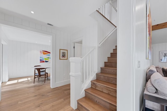 staircase featuring wood walls and hardwood / wood-style floors