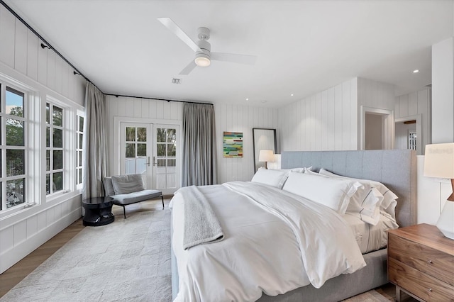 bedroom with multiple windows, ceiling fan, french doors, and light hardwood / wood-style flooring