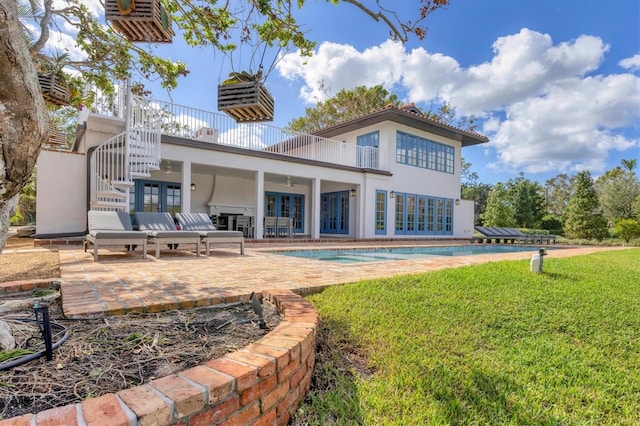 back of property with ceiling fan, a patio area, and a yard