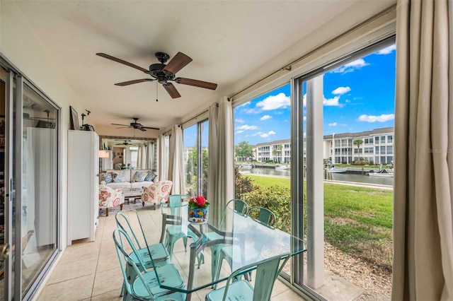 sunroom / solarium featuring ceiling fan and a water view