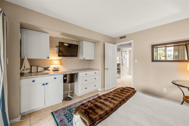 bedroom featuring light tile patterned floors and built in desk