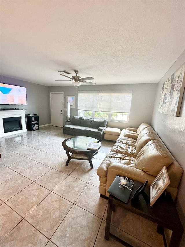 tiled living room with ceiling fan and a textured ceiling