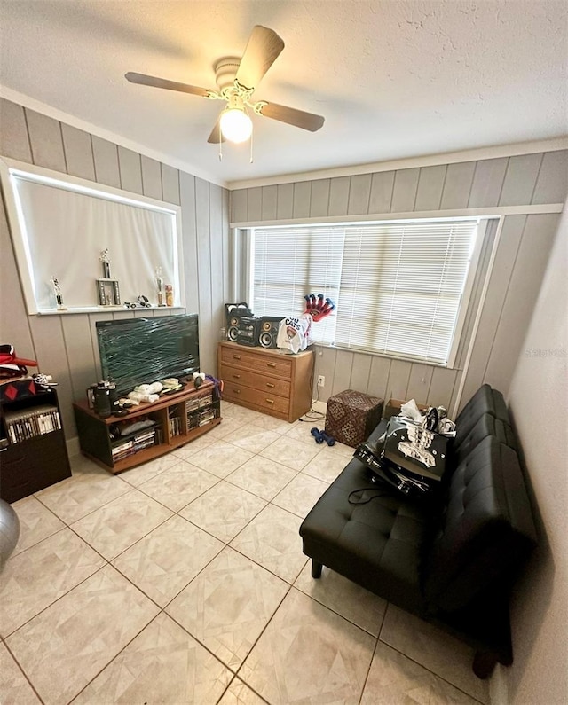 living area with ceiling fan, crown molding, light tile patterned floors, and a textured ceiling