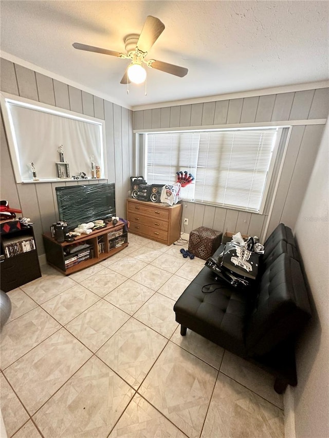 sitting room with ceiling fan, light tile patterned floors, and a textured ceiling