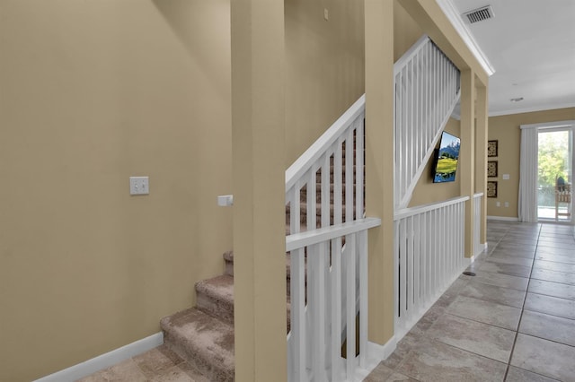 stairway with tile patterned floors and crown molding