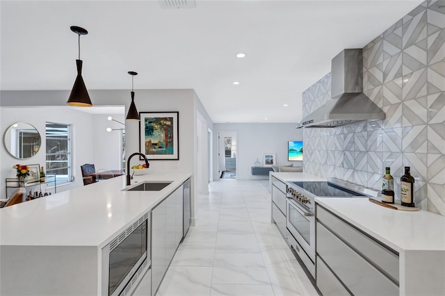 kitchen with a large island, hanging light fixtures, stainless steel appliances, wall chimney range hood, and decorative backsplash