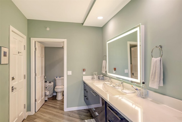 bathroom with toilet, vanity, and hardwood / wood-style floors