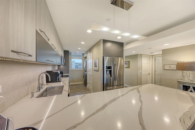 kitchen featuring stainless steel appliances, light stone countertops, light brown cabinets, and sink