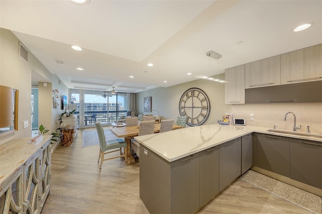 kitchen with light stone counters, ceiling fan, light hardwood / wood-style flooring, kitchen peninsula, and gray cabinets