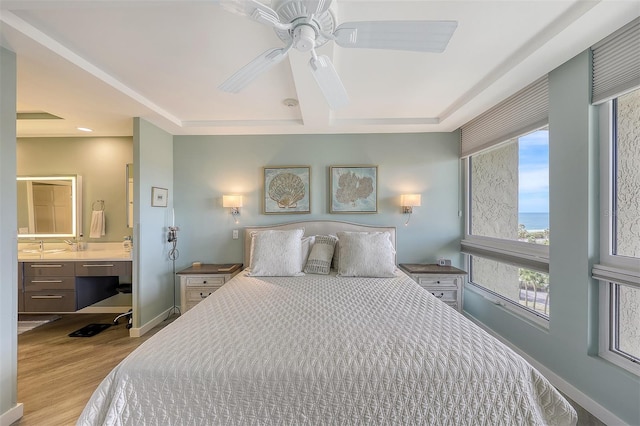 bedroom with connected bathroom, multiple windows, ceiling fan, and light wood-type flooring