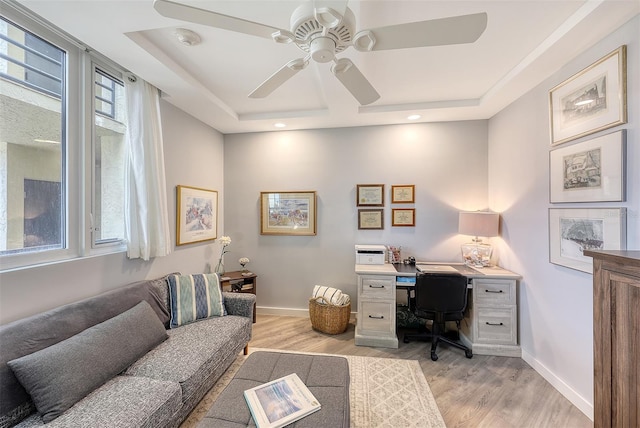 office area featuring light hardwood / wood-style floors, ceiling fan, and a tray ceiling