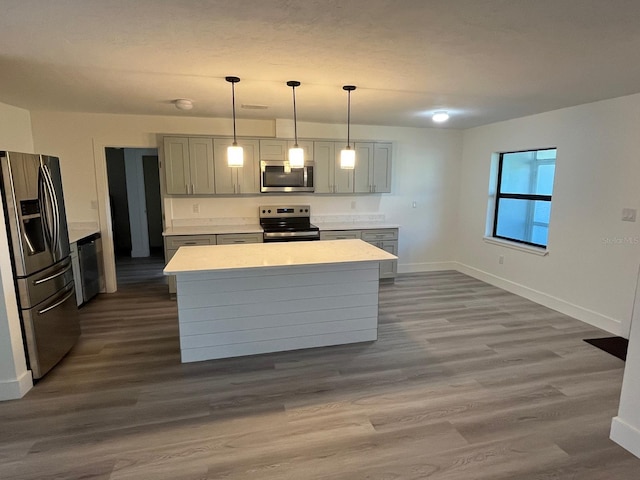 kitchen with gray cabinetry, a center island, hanging light fixtures, stainless steel appliances, and dark hardwood / wood-style flooring