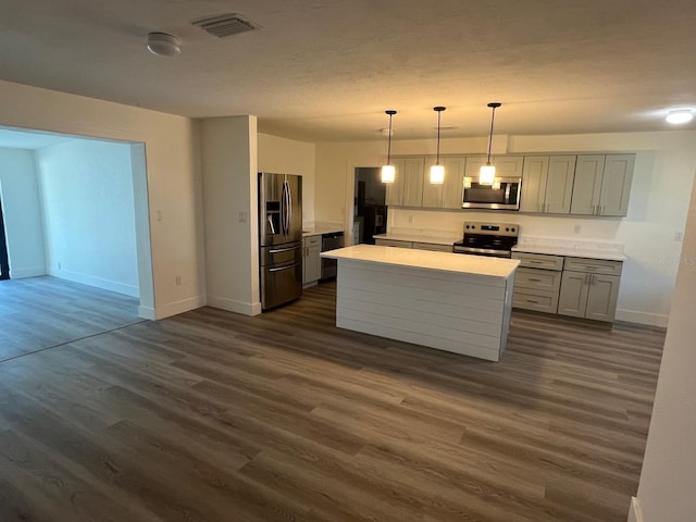 kitchen with pendant lighting, gray cabinetry, a center island, dark wood-type flooring, and stainless steel appliances