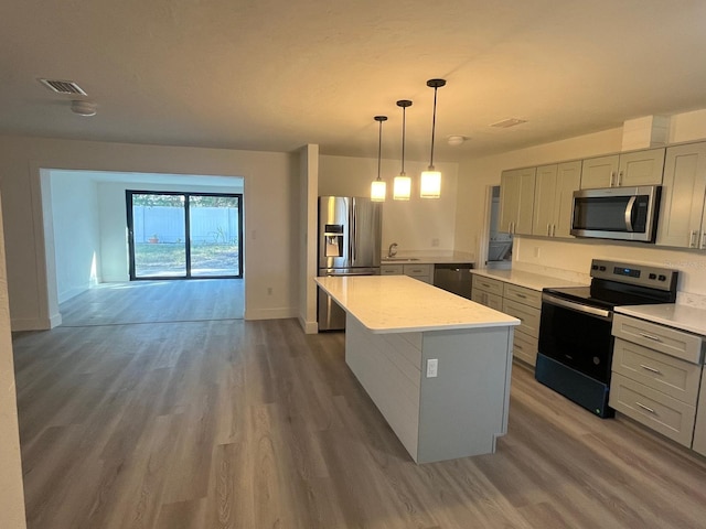 kitchen featuring a center island, dark hardwood / wood-style floors, gray cabinets, decorative light fixtures, and stainless steel appliances