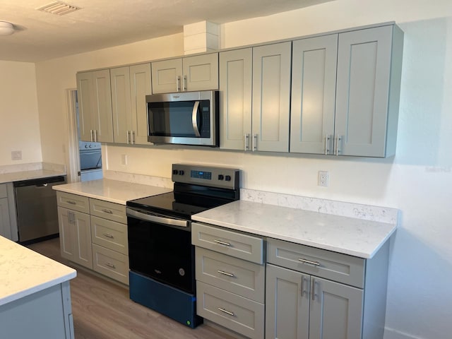 kitchen featuring stainless steel appliances, dark hardwood / wood-style floors, and gray cabinetry