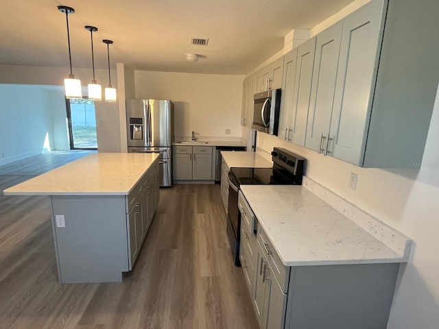 kitchen featuring light stone countertops, dark hardwood / wood-style floors, decorative light fixtures, a kitchen island, and appliances with stainless steel finishes