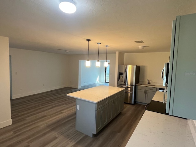 kitchen featuring stainless steel fridge, sink, decorative light fixtures, a center island, and dark hardwood / wood-style floors