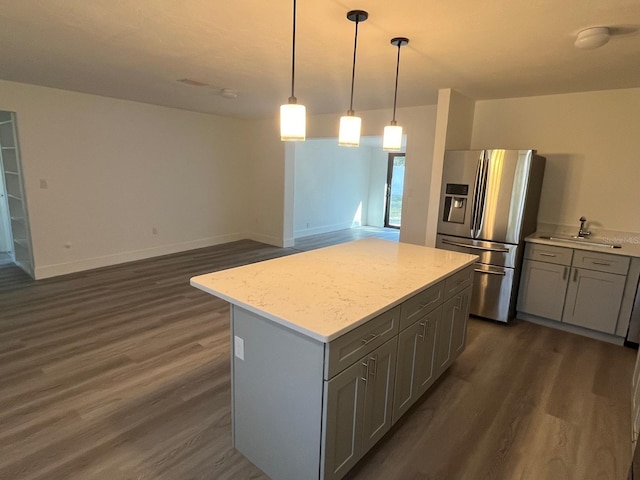 kitchen with stainless steel refrigerator with ice dispenser, gray cabinets, a center island, dark hardwood / wood-style floors, and hanging light fixtures