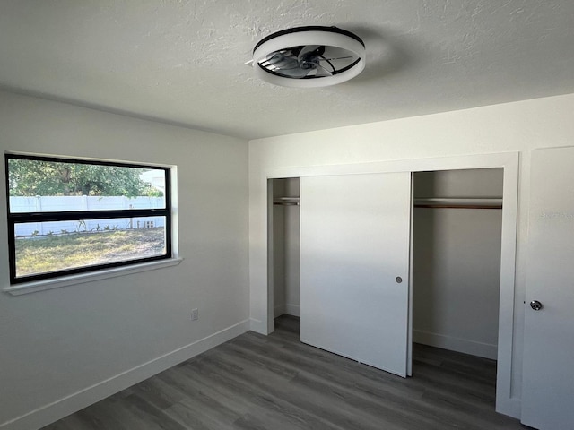 unfurnished bedroom featuring dark hardwood / wood-style flooring, a textured ceiling, and a closet