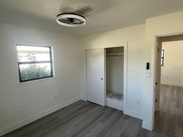 unfurnished bedroom with dark hardwood / wood-style floors and a closet