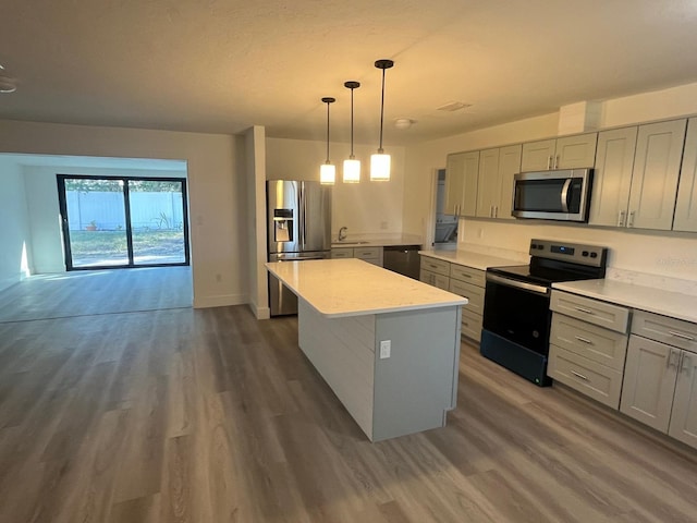 kitchen with black appliances, gray cabinets, decorative light fixtures, a kitchen island, and dark hardwood / wood-style flooring