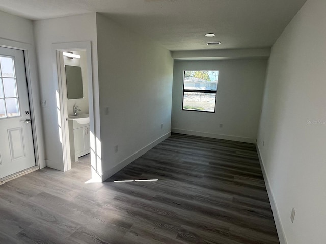 spare room featuring sink and dark wood-type flooring