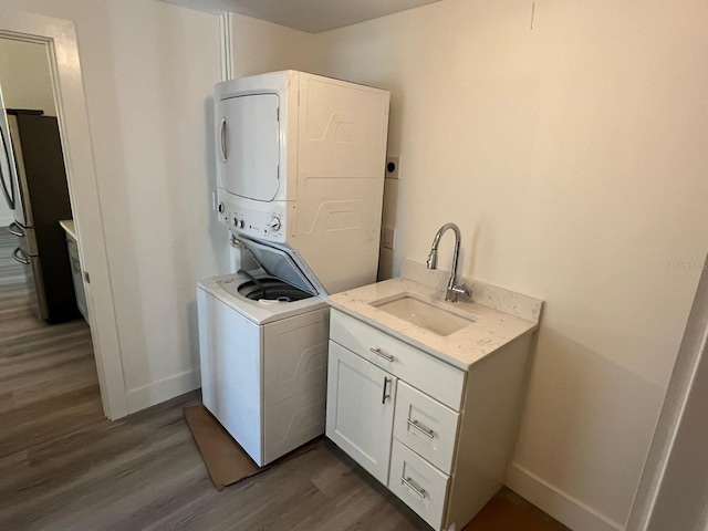 laundry room featuring cabinets, dark hardwood / wood-style floors, sink, and stacked washer / dryer