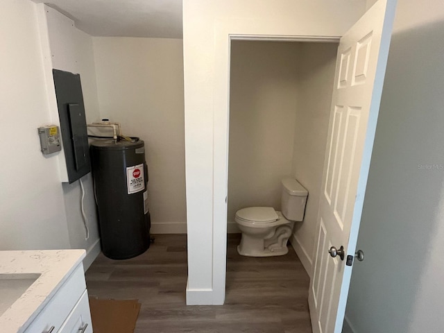 bathroom with vanity, electric water heater, electric panel, toilet, and wood-type flooring